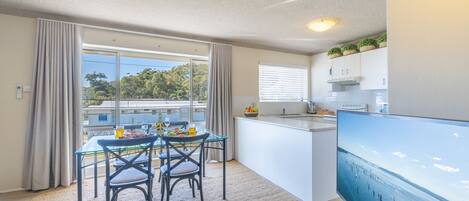 Una cocina moderna con comedor, ventanas amplias y un televisor de pantalla plana.