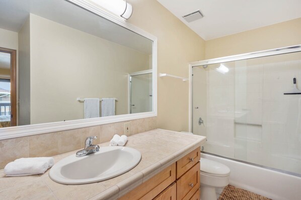 A bathroom with a sink, mirror, vanity, and a glass-enclosed shower.