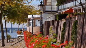 Ein Hotel am Wasser mit Ziegel-Fassade, einem Balkon mit Glasgeländer und Blick auf den Fluss.