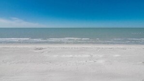 Ein Strand mit blauem Himmel und ruhigem Meer.