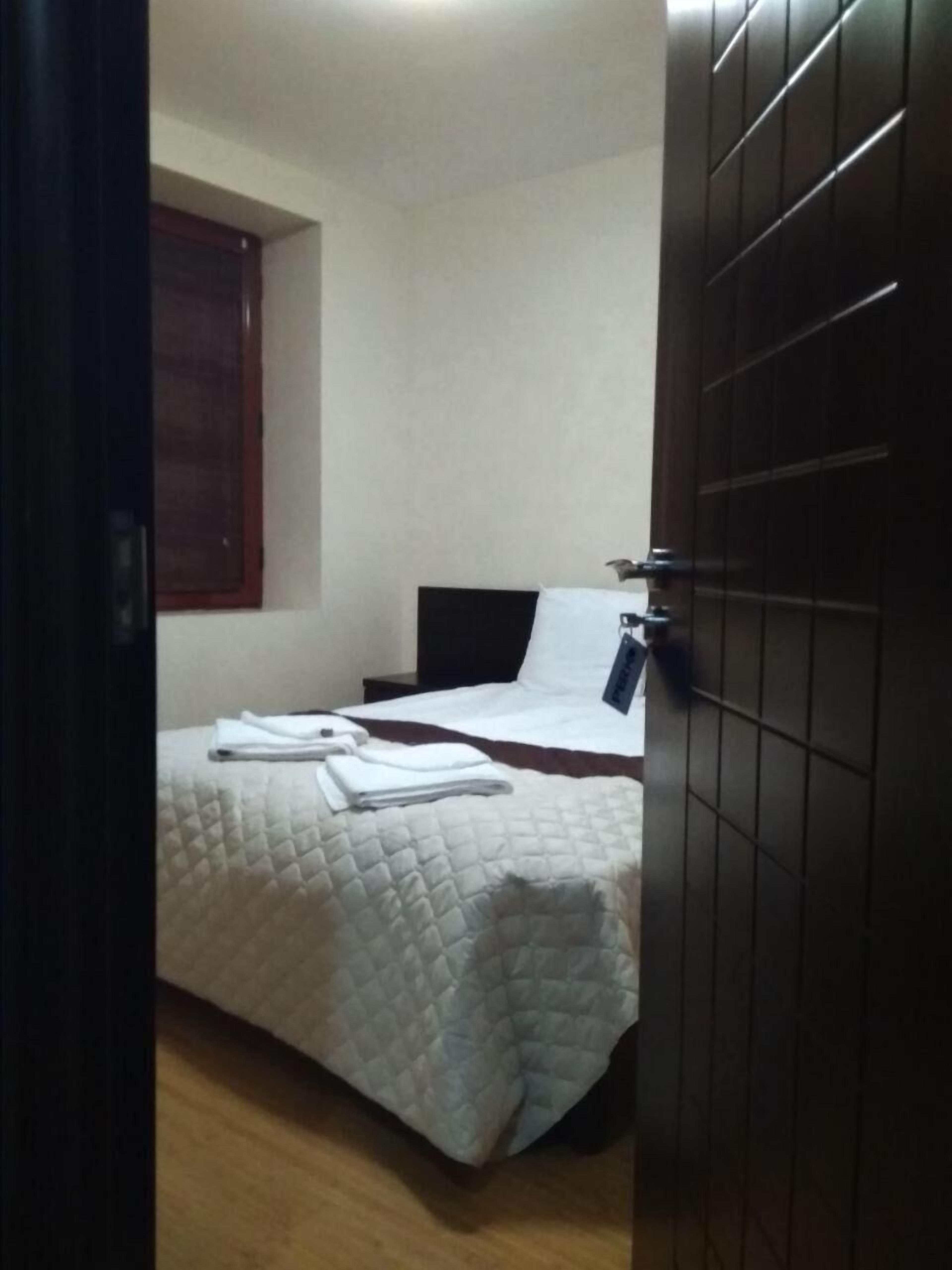 A bedroom with a bed, a window, and a door.