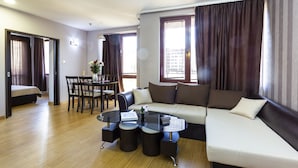 A modern living room with a sofa, coffee table, and dining area. - CityHome Aparthotel (Sofia)
