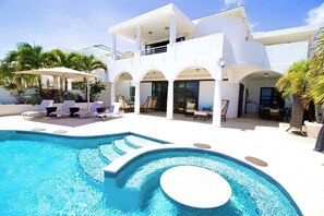 Un complexe hôtelier moderne doté d’une piscine, de chaises longues et d’un patio couvert.