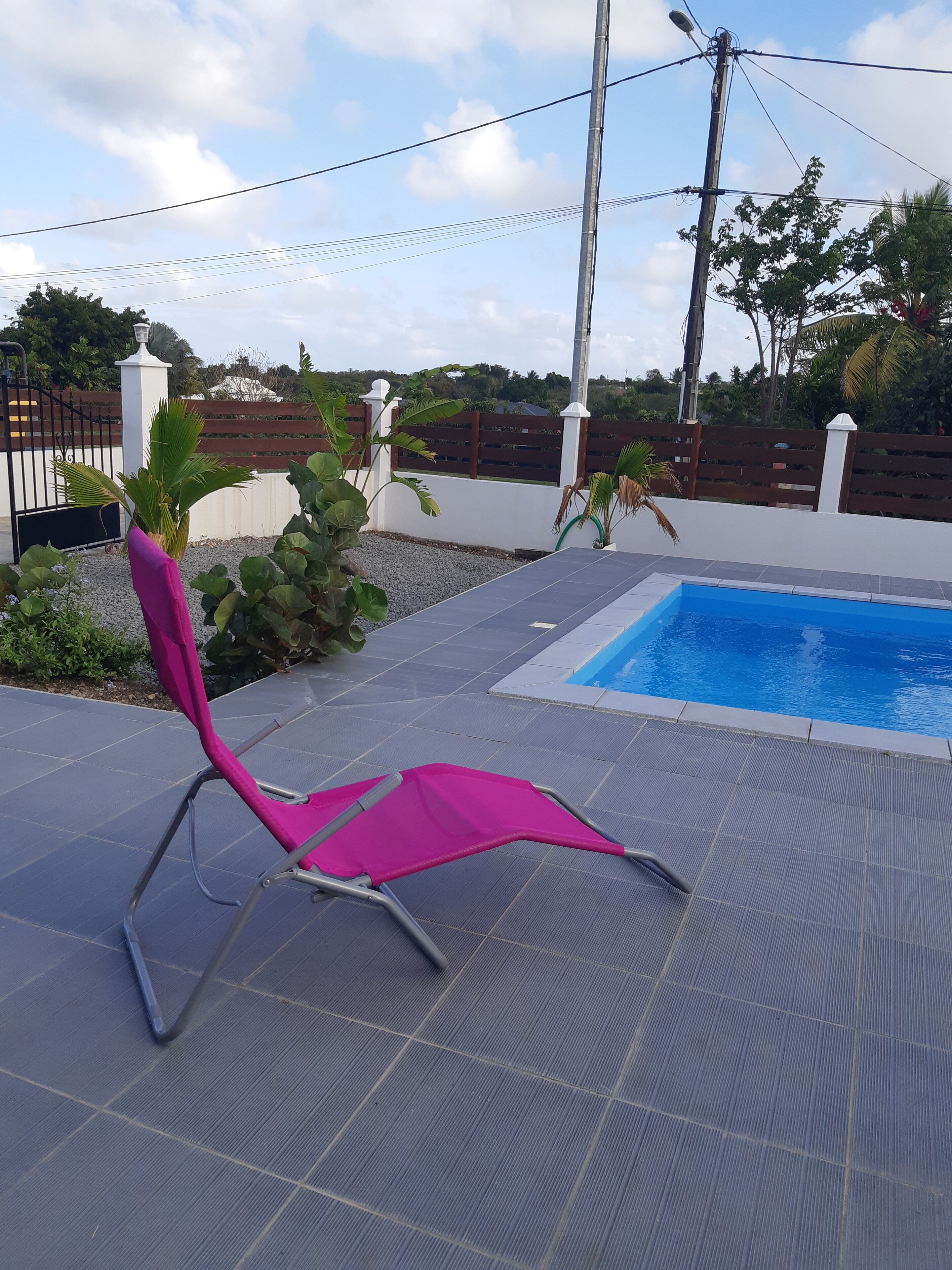 Ein Poolbereich mit gefliestem Deck, einem Pool und einem rosa Stuhl.