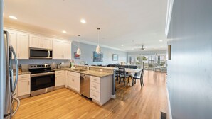 Une cuisine moderne dotée d’appareils électroménagers en acier inoxydable, de meubles blancs et d’un plancher en bois.
