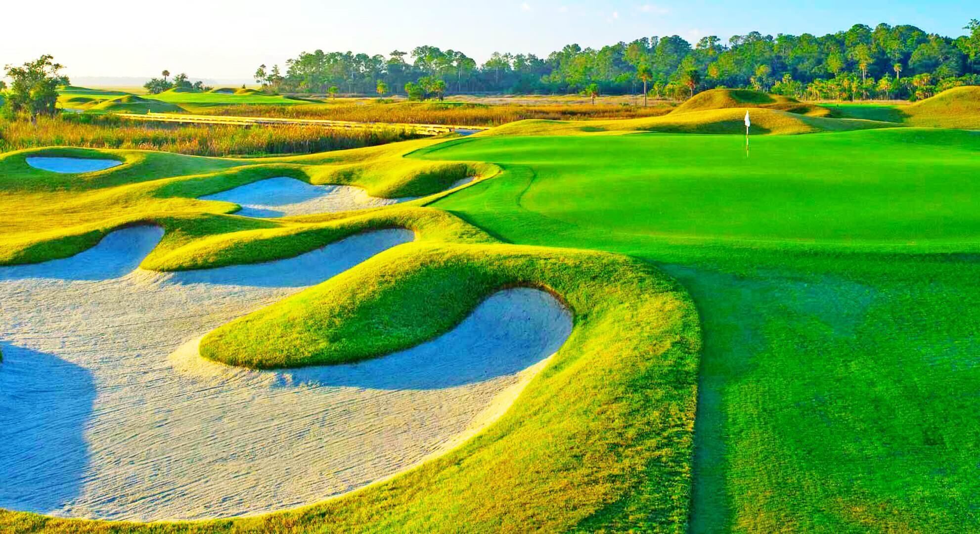 Un parcours de golf avec des bunkers de sable, des obstacles d’eau et un mât de drapeau.
