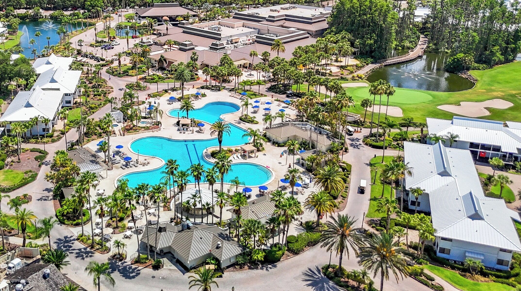 Vue aérienne d’un complexe hôtelier doté de plusieurs piscines, de palmiers et de terrains de golf.