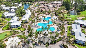 Vue aérienne d’un complexe hôtelier doté de plusieurs piscines, de palmiers et d’un parcours de golf.