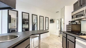 A modern kitchen with a stainless steel sink, a bar stool, and a built-in stove.