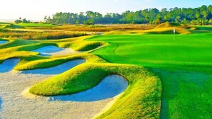 A golf course with sand bunkers and a flag on the green. - PgaVillageResort by AmericanVacationLiving 7 Room (Port Saint Lucie)