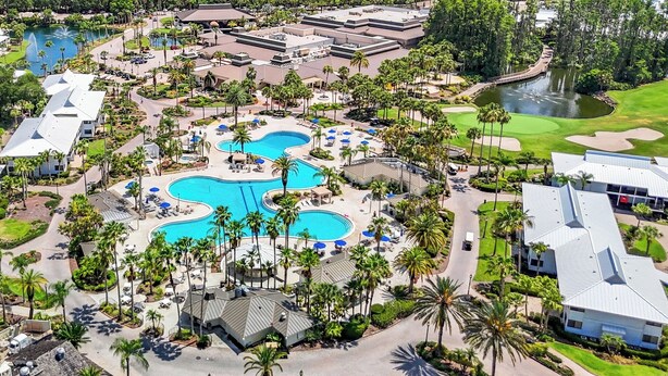 An aerial view of a resort with multiple swimming pools, palm trees, and golf courses.