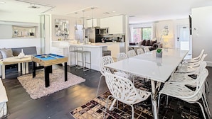 A modern kitchen with white cabinets, a central island, and bar stools.