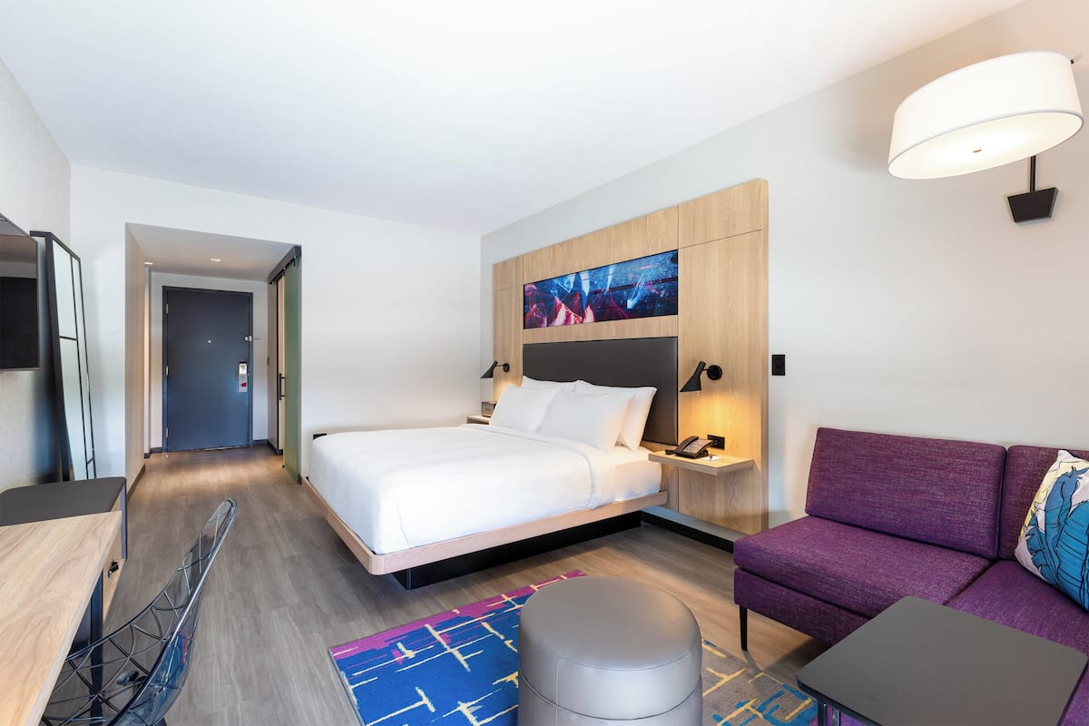 Una habitación de hotel moderna con cama, sofá, escritorio y televisor.