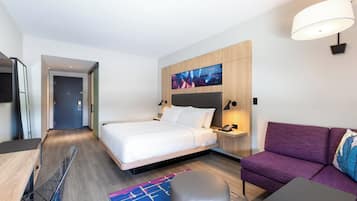 Una habitación de hotel moderna con cama, sofá, escritorio y televisor.