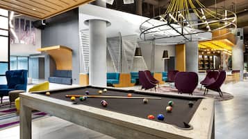 A modern pool table in a spacious lounge area with comfortable seating and a unique ceiling design.
