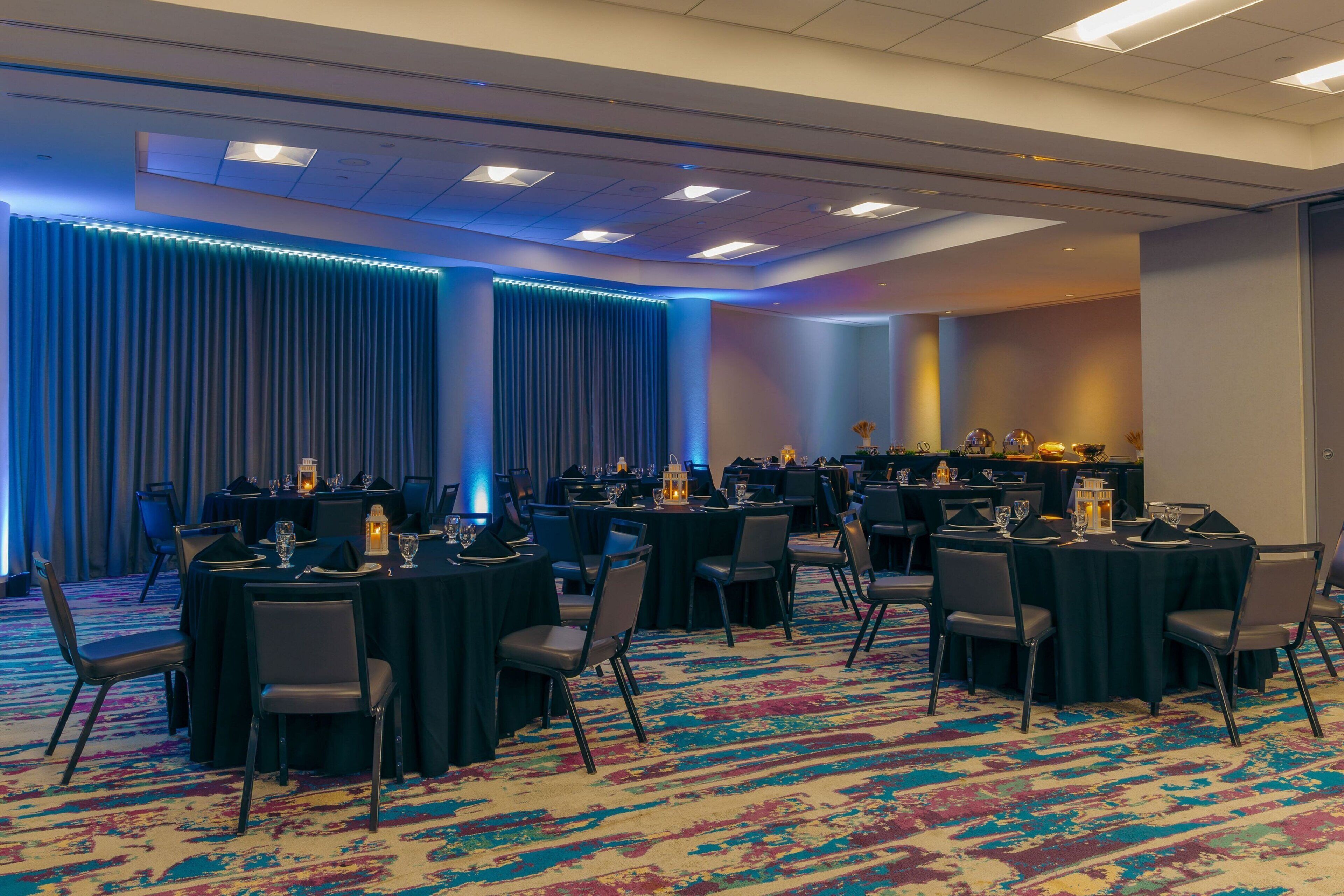 A conference room with round tables, chairs, and a carpeted floor.