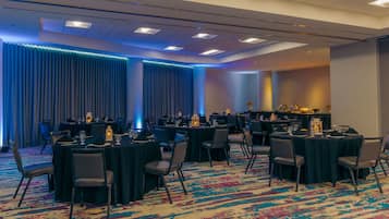 A conference room with round tables, chairs, and a carpeted floor.