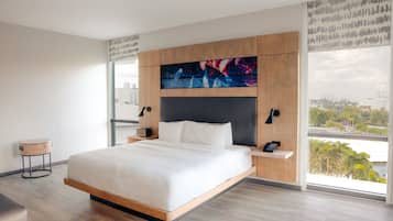 Habitación de hotel moderna con una cama grande, vista a la ciudad y un diseño contemporáneo.