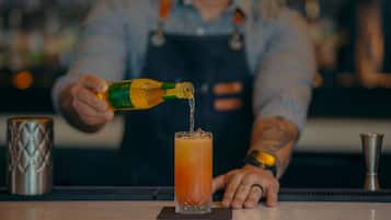 Un bartender sirve una bebida en un vaso alto.