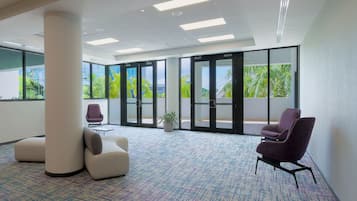 Un espacio de oficina moderno con alfombra estampada, un pilar grande y una silla morada.
