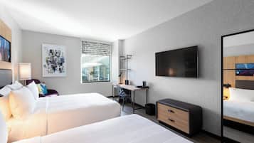 A hotel room with two beds, a desk, a chair, a TV, and a large window.