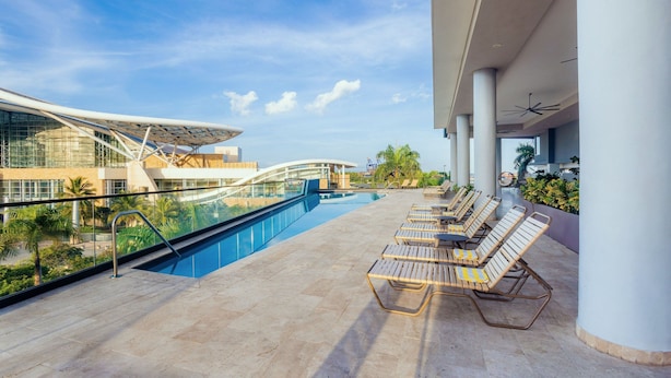 Zona de piscina en la azotea con sillones, barandilla de vidrio y arquitectura moderna.