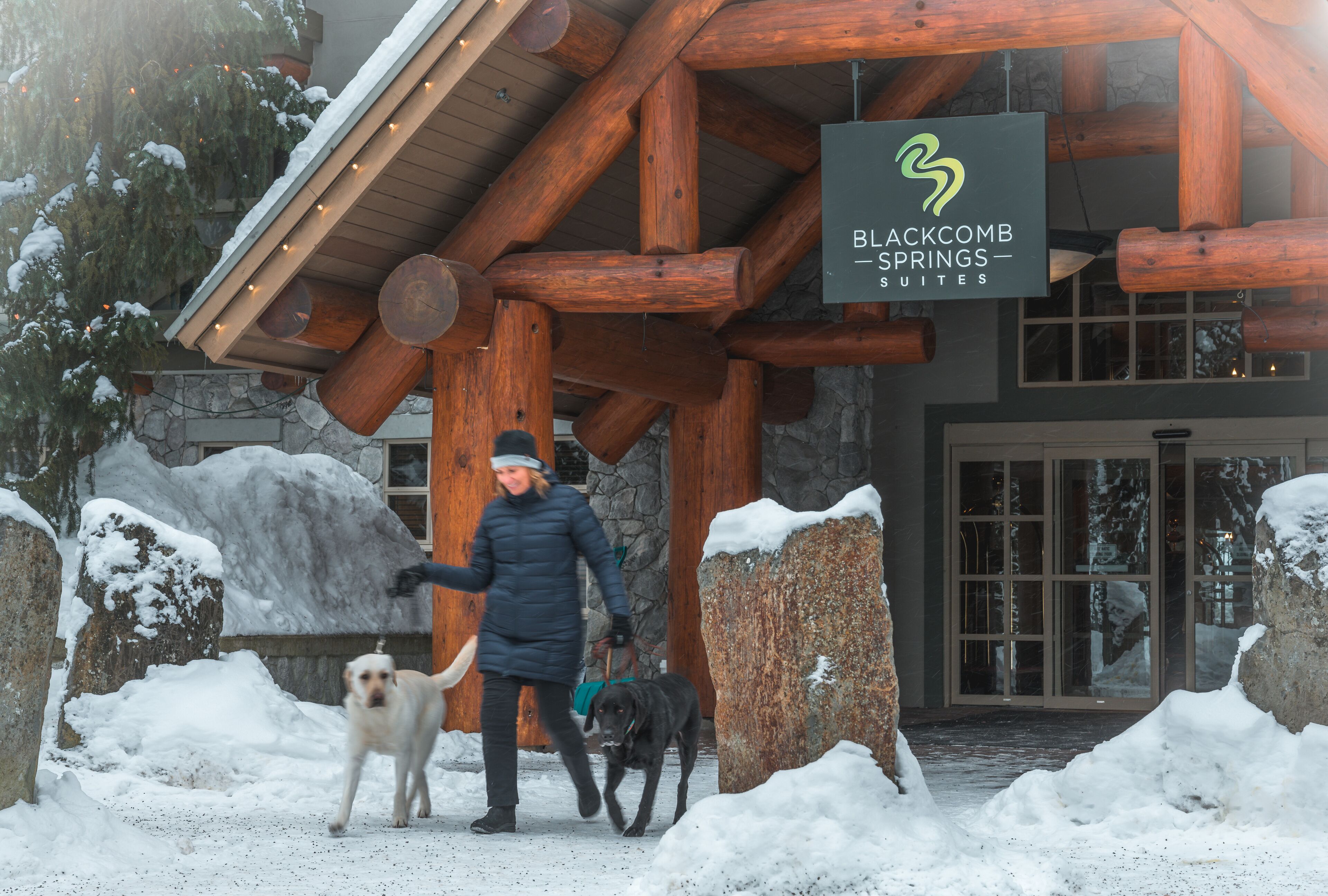 Um edifício em estilo de cabana de toras com uma placa indicando Blackcomb Springs Suites.