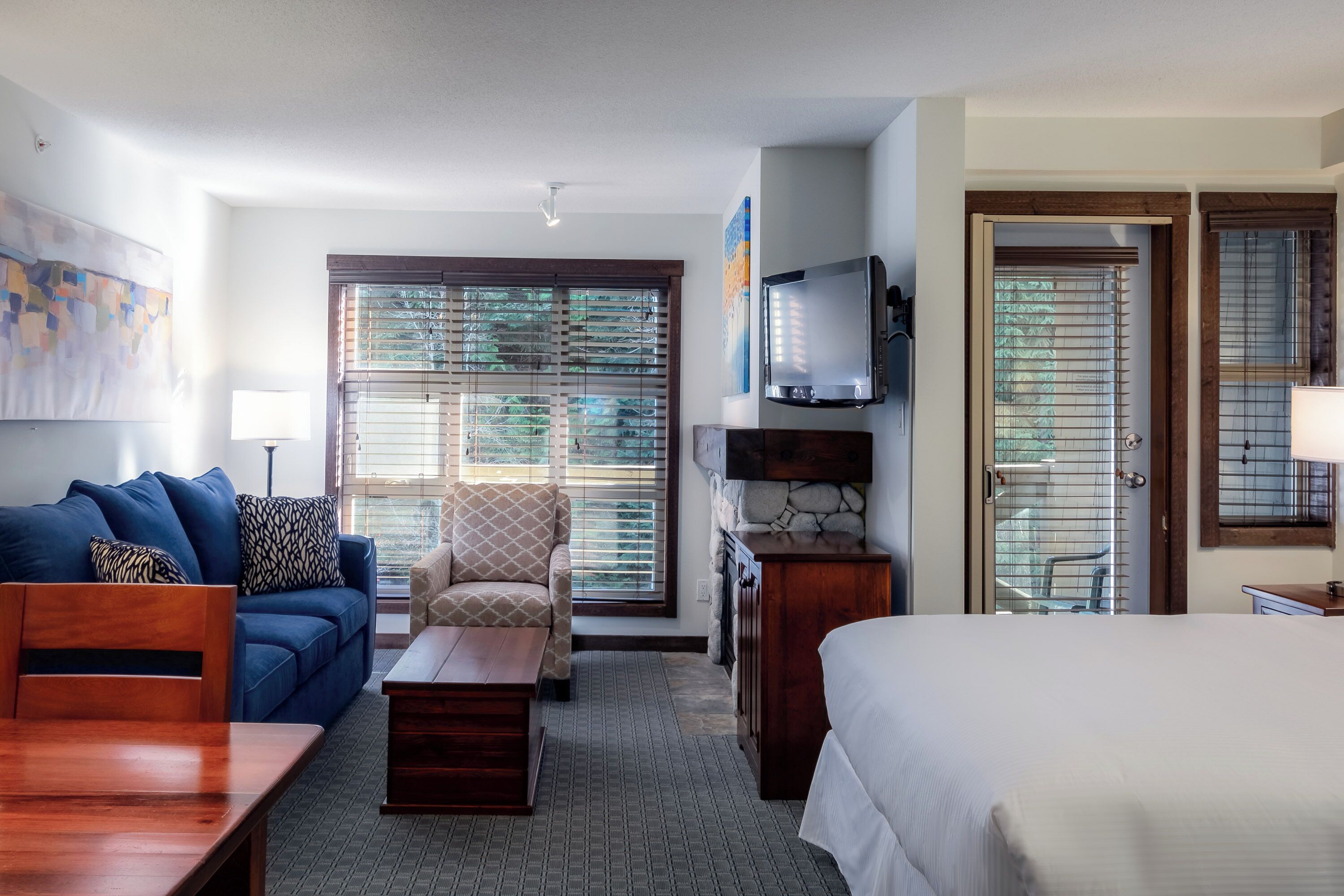 A hotel room with a bed, a sofa, a chair, a TV, and a desk.