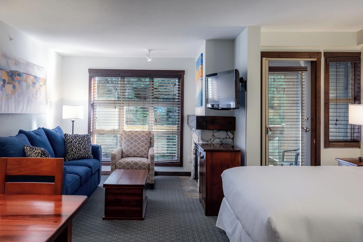 A hotel room with a bed, a sofa, a chair, a TV, and a desk.