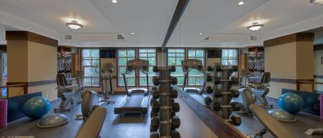 Ett gym med träningsutrustning, löpband och en vägg med speglar.