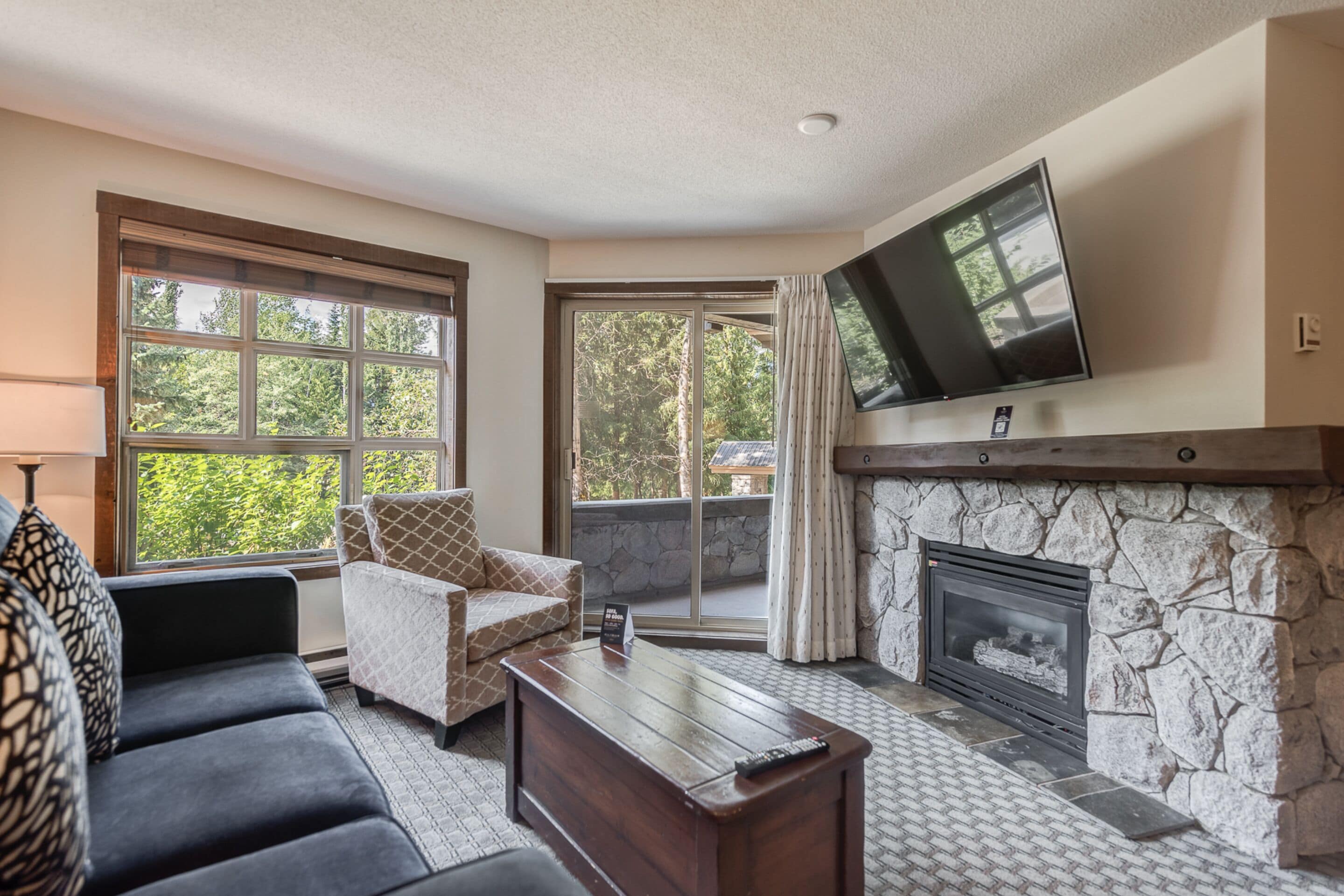 A living room with a fireplace, a sofa, a coffee table, and a TV mounted on the wall.