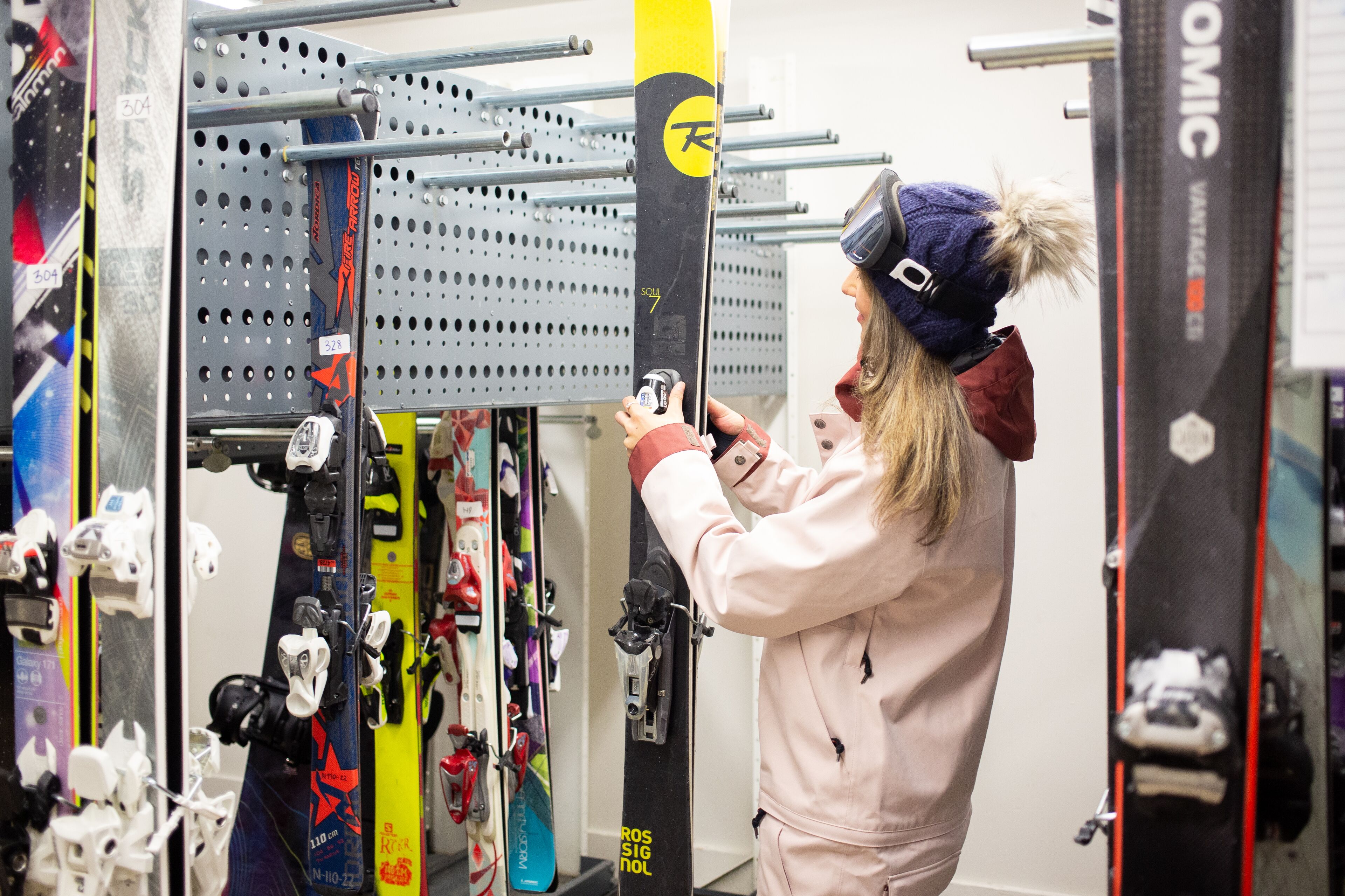 A person adjusting ski bindings on a rack.