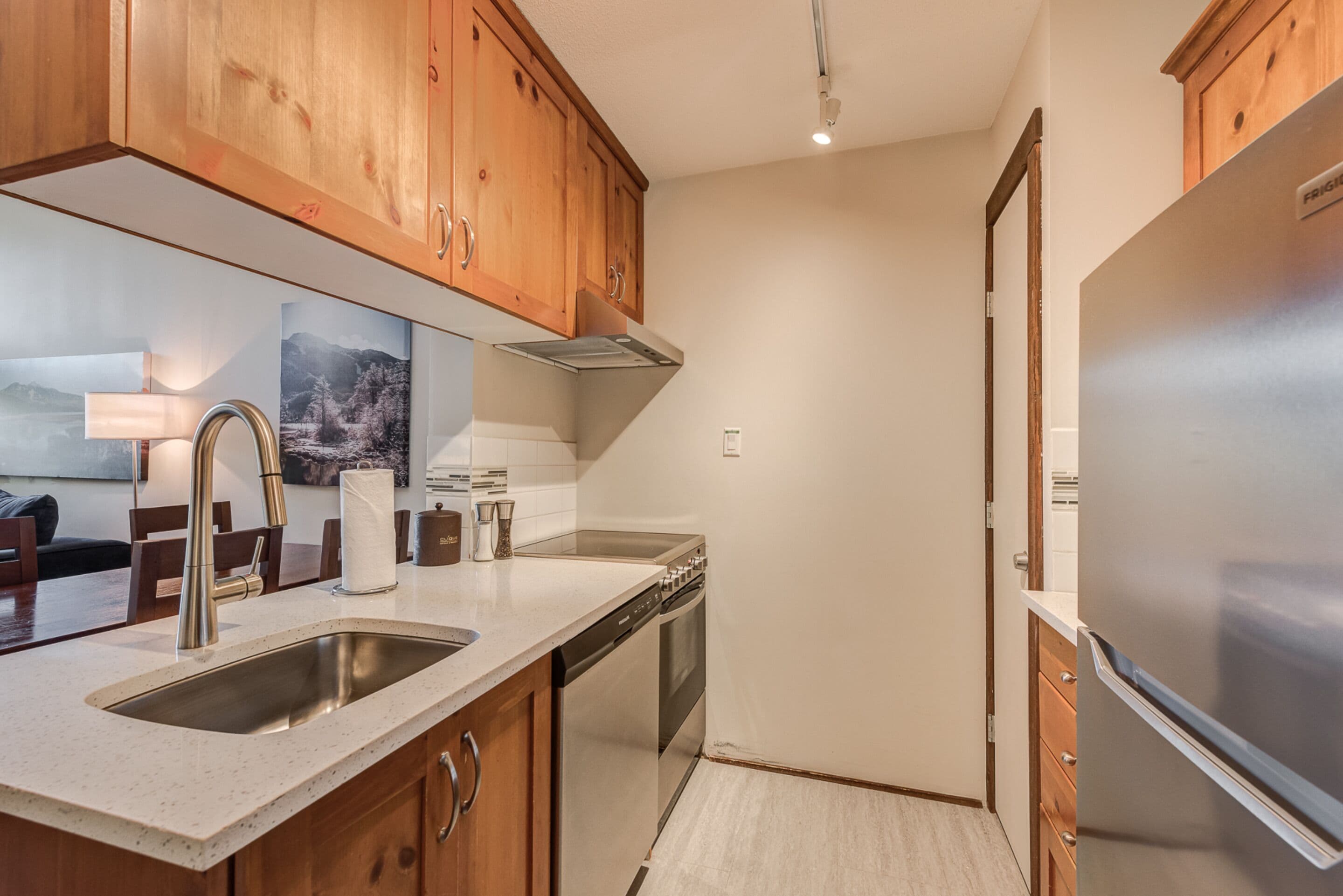 A kitchen with wooden cabinets, stainless steel appliances, a dishwasher, and a countertop with a sink.
