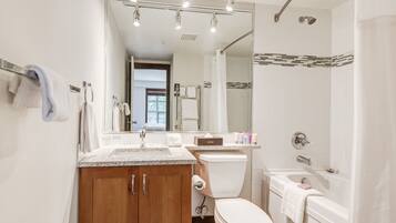A modern bathroom with a wooden vanity, a toilet, a sink, and a bathtub.
