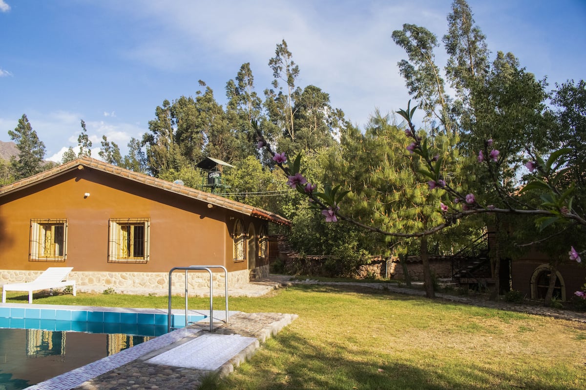 Una casa con piscina, césped y árboles.