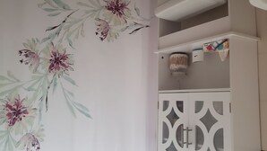 A bathroom with a floral shower curtain, a white cabinet with geometric patterns, and a ceiling light fixture. - Ocean Park 2nd Floor King-Size Mini-Studio (Santurce)