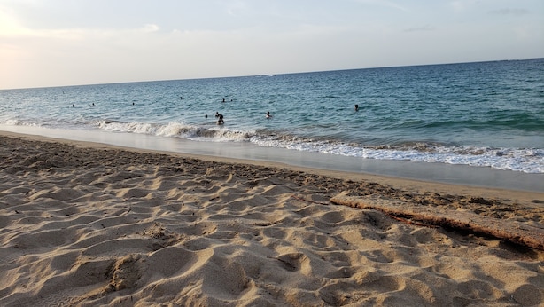A sandy beach with footprints leading to the water, a clear sky, and a calm sea. - Ocean Park 2nd Floor King-Size Mini-Studio (Santurce)