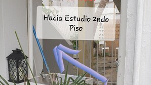 A narrow outdoor corridor with a white wall, a black lantern, and a blue broom leaning against it. - Ocean Park 2nd Floor King-Size Mini-Studio (Santurce)