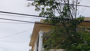 A two-story house with a covered entrance, potted plants, and a gated driveway. - Ocean Park 2nd Floor King-Size Mini-Studio (Santurce)