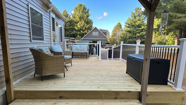 A wooden deck with outdoor furniture, a grill, and a covered area with a grill.