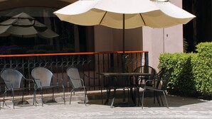 A pool area with a seating arrangement, including chairs and a table, and a ceiling fan above. - Estancia Inn (Tecate)