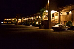 Un hotel con una hilera de habitaciones, un patio central y un coche estacionado.