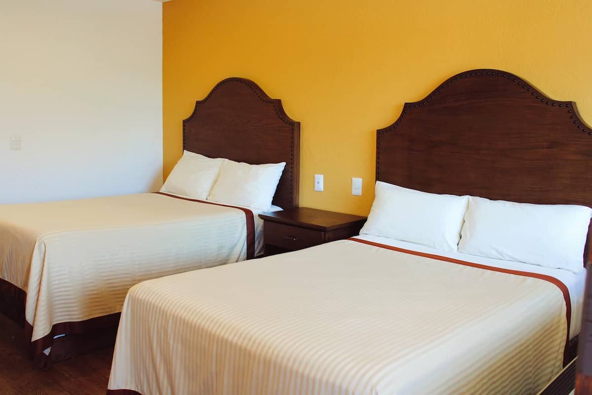 Two single beds with wooden headboards, white bedding, and a wooden nightstand between them.