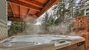 Un bain à remous dont la vapeur s’élève, entouré d’une terrasse en bois et d’arbres.