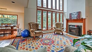 Un salon spacieux avec un plafond haut, de grandes fenêtres, une cheminée et un tapis aux couleurs vives.