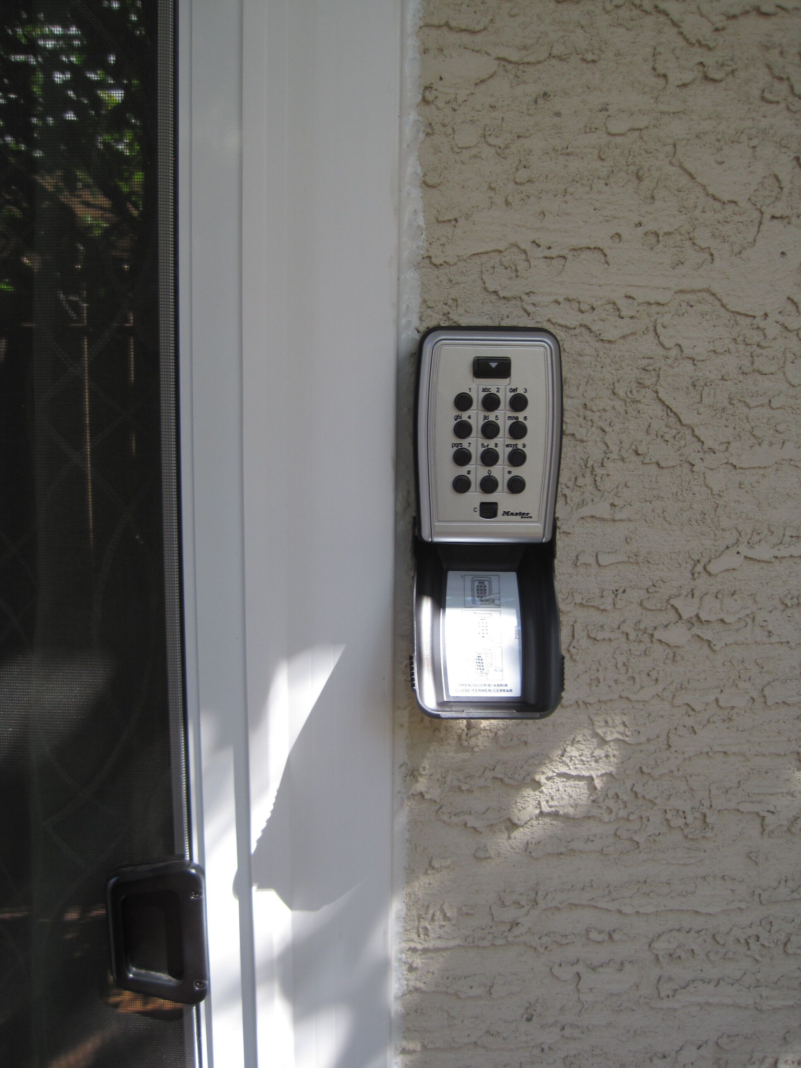 A wall-mounted intercom system with a keypad and a display panel.