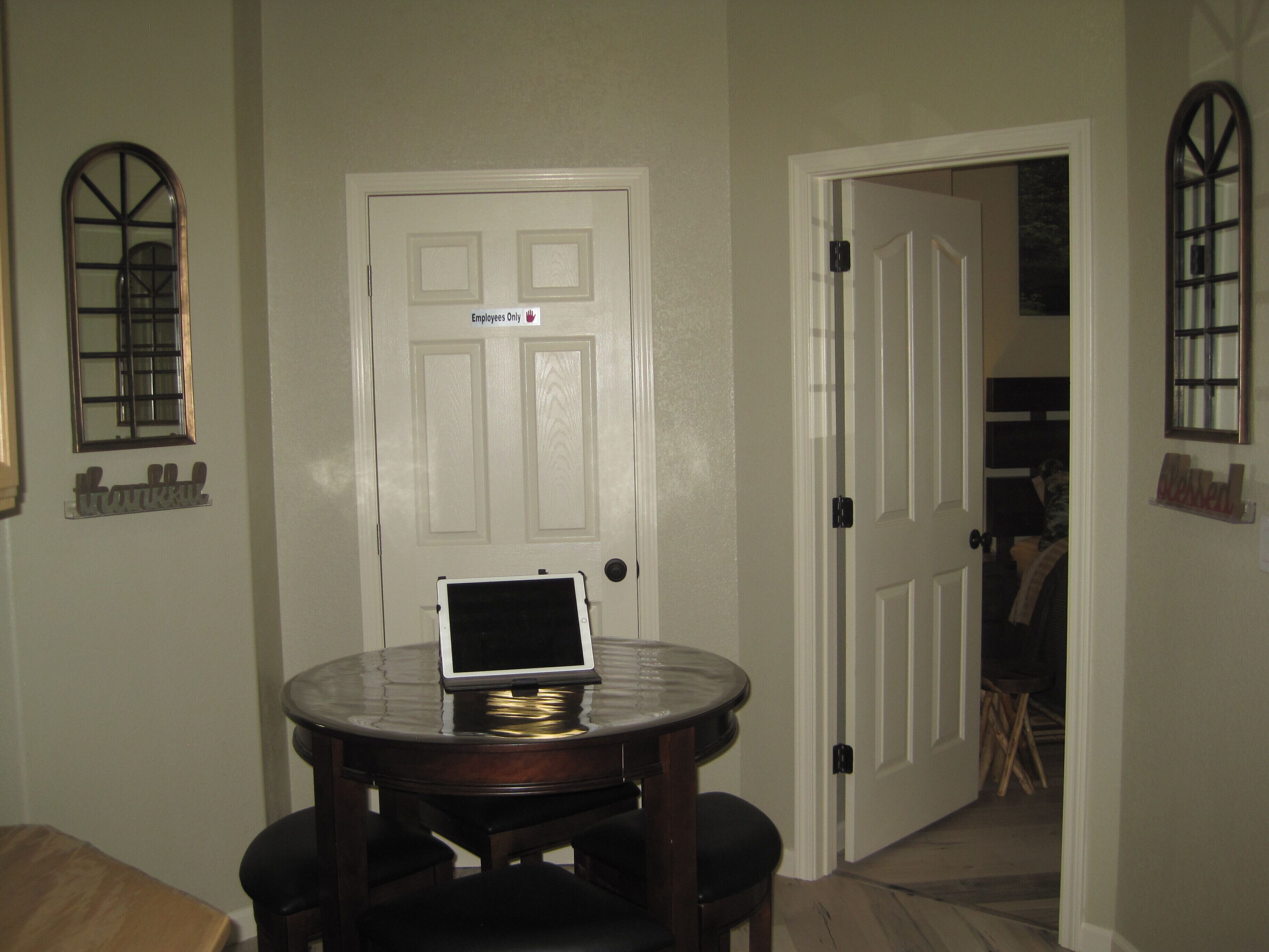 Una habitación con puerta cerrada, una pequeña mesa con un ordenador portátil y una silla.