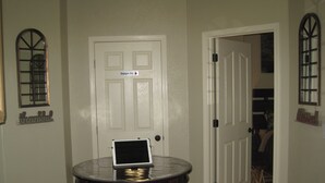 A room with a closed door, a small table with a laptop, and a chair.