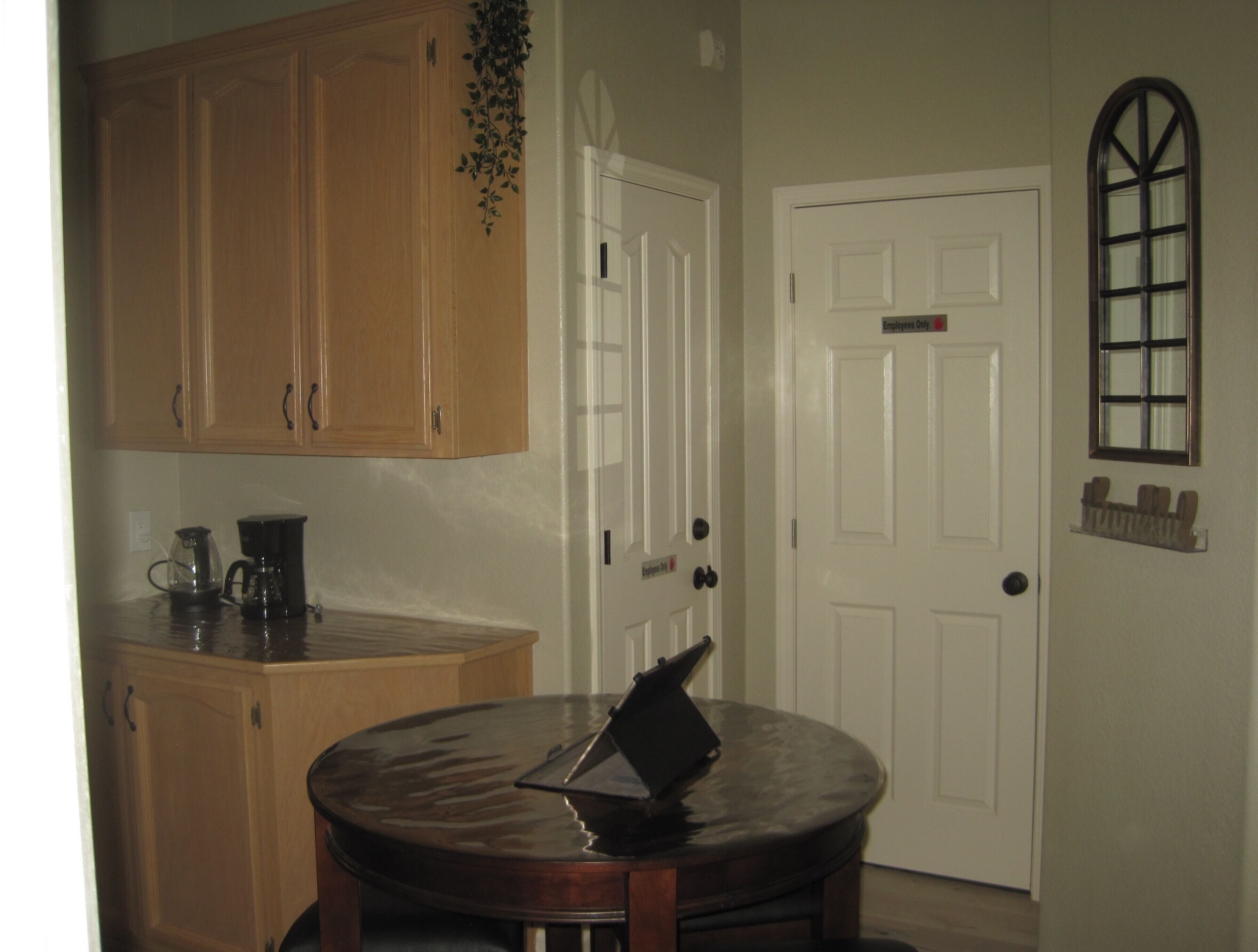 A kitchen with wooden cabinets, a coffee maker, and a round table with a laptop.