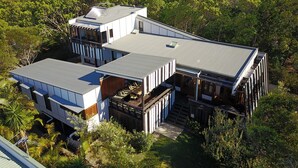 Une maison moderne à plusieurs niveaux, dotée de grandes fenêtres et d’un toit plat.
